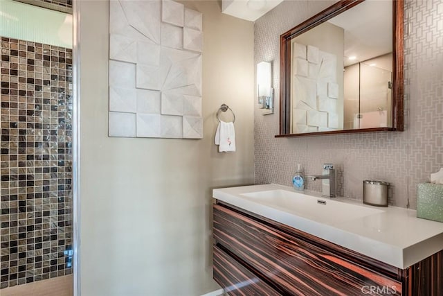 bathroom with vanity, tasteful backsplash, and a tile shower