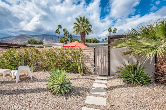 view of yard featuring a mountain view, fence, and a gate