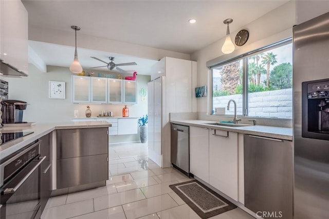 kitchen featuring a ceiling fan, a sink, white cabinetry, stainless steel appliances, and light countertops