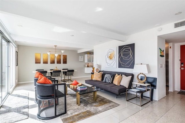 living room with beam ceiling, visible vents, speckled floor, and baseboards