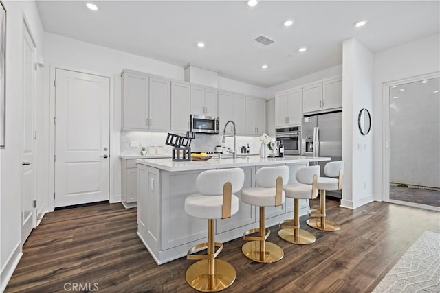 392 Baluster, Irvine, CA 92618 - kitchen with visible vents, dark wood finished floors, light countertops, an island with sink, and stainless steel appliances