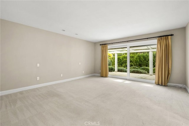 spare room with baseboards and light carpet