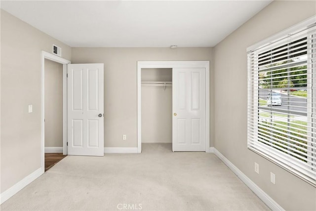 unfurnished bedroom featuring a closet, visible vents, light colored carpet, and baseboards