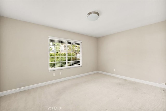 unfurnished room featuring baseboards and light carpet