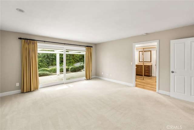 empty room featuring baseboards and light carpet