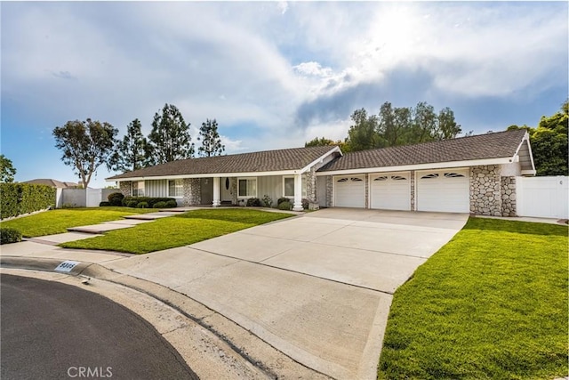 single story home with a front lawn, fence, concrete driveway, stone siding, and an attached garage