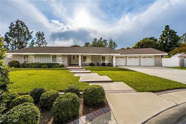 single story home with a front yard, fence, concrete driveway, a garage, and stone siding