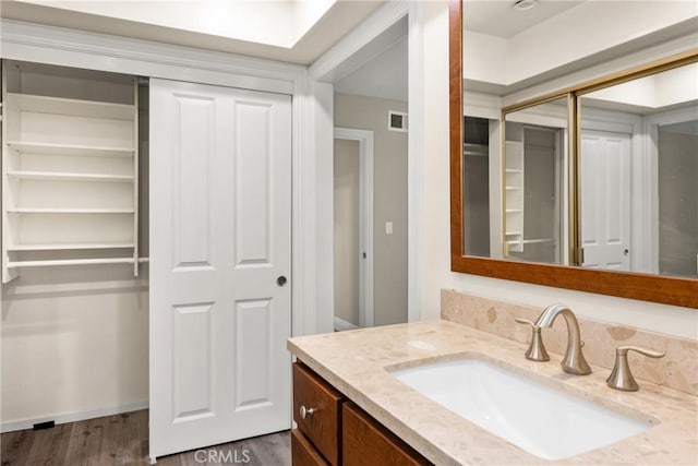 bathroom featuring visible vents, vanity, baseboards, and wood finished floors