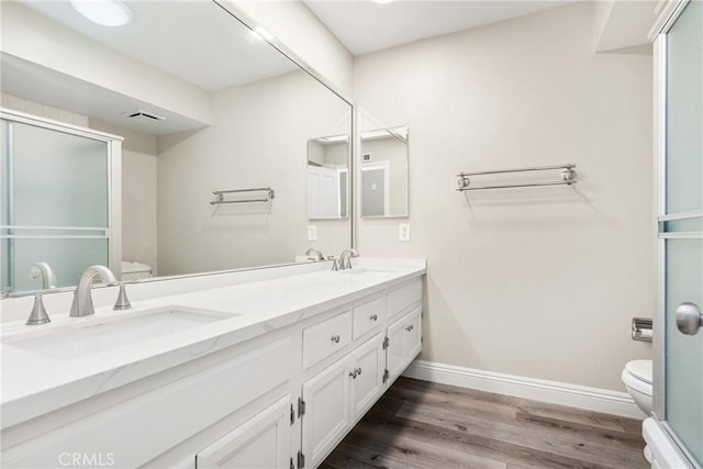 bathroom with wood finished floors, toilet, baseboards, and a sink