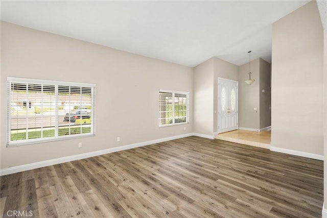 spare room with vaulted ceiling, baseboards, and wood finished floors