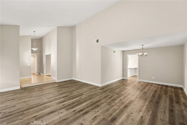 spare room featuring visible vents, baseboards, wood finished floors, and a chandelier