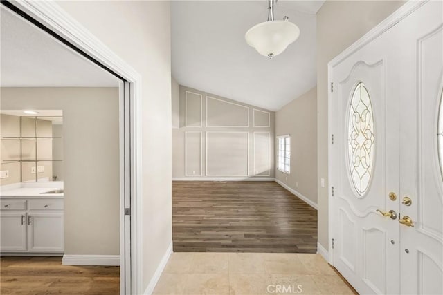 entrance foyer featuring light tile patterned floors, baseboards, and lofted ceiling