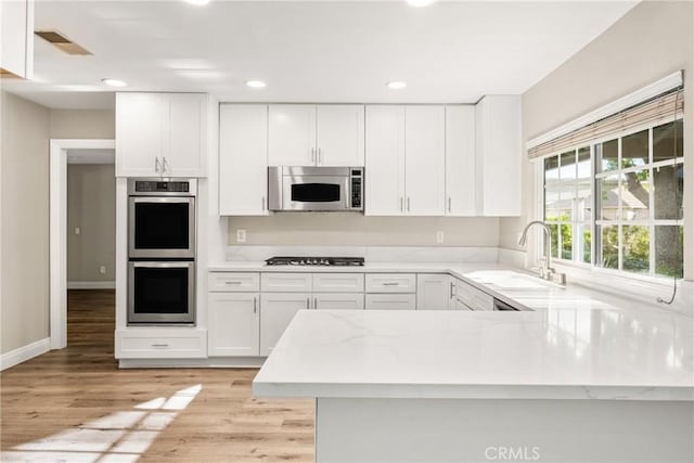 kitchen with a sink, visible vents, appliances with stainless steel finishes, and white cabinets