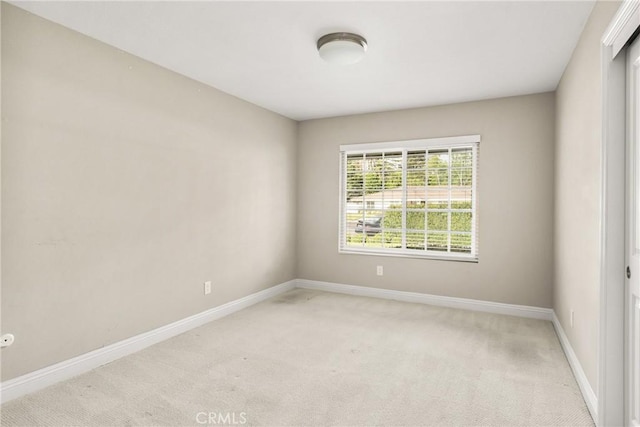 empty room with baseboards and light colored carpet