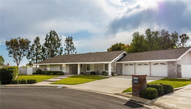 ranch-style house featuring fence, a front yard, a garage, stone siding, and driveway