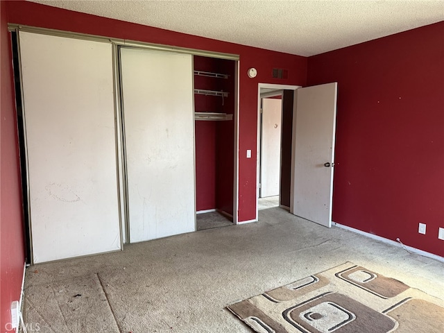 unfurnished bedroom featuring a closet, a textured ceiling, visible vents, and carpet flooring