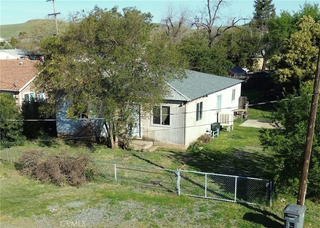 view of home's exterior featuring a lawn, roof with shingles, and fence