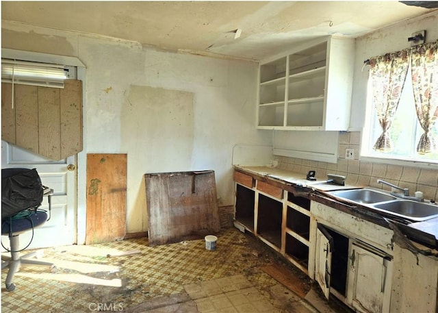 kitchen featuring backsplash, open shelves, and a sink