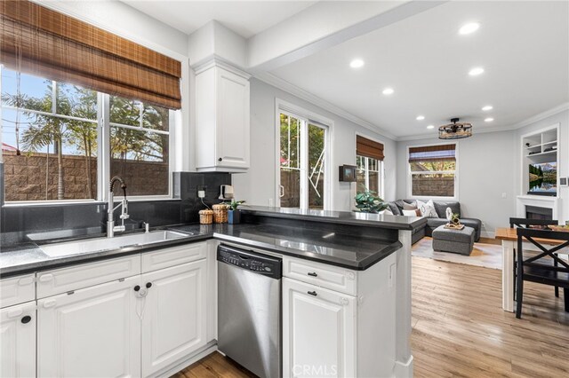 kitchen featuring a peninsula, ornamental molding, a sink, stainless steel dishwasher, and open floor plan