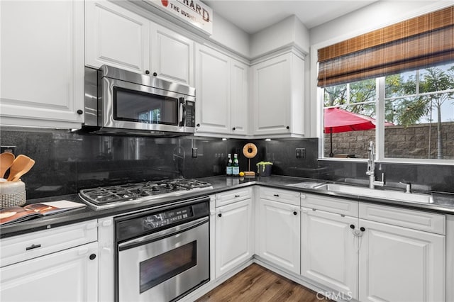 kitchen featuring dark countertops, appliances with stainless steel finishes, white cabinetry, and a sink