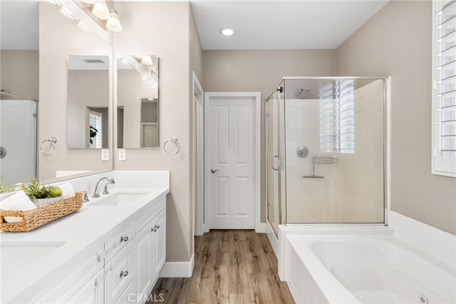 bathroom featuring visible vents, double vanity, a stall shower, a sink, and a garden tub