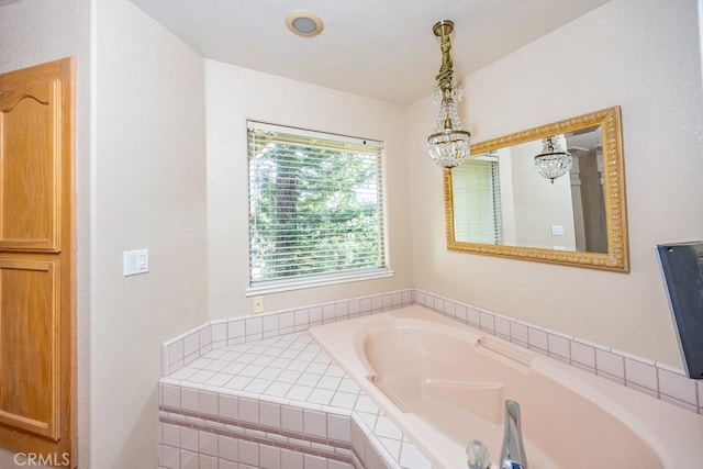 bathroom with a notable chandelier, a textured ceiling, and a bath