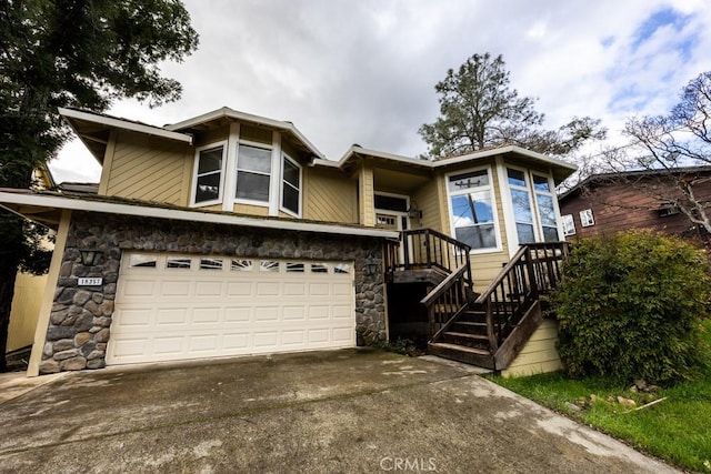 view of front of house featuring stone siding, an attached garage, and concrete driveway