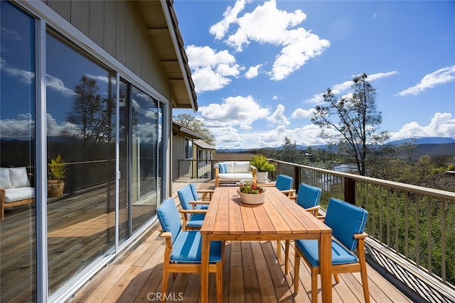 wooden deck with outdoor dining space and a mountain view