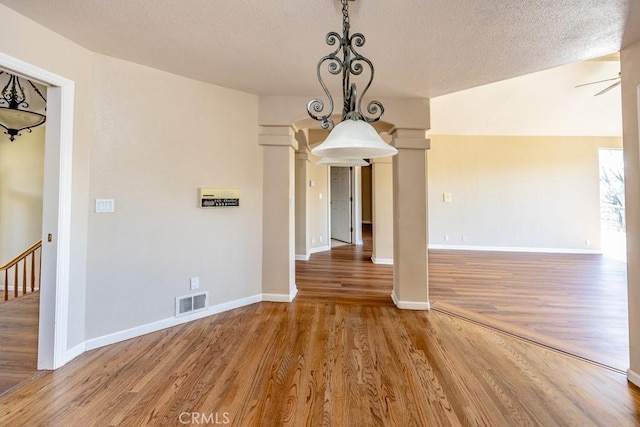 unfurnished dining area featuring a textured ceiling, light wood-style floors, visible vents, and baseboards