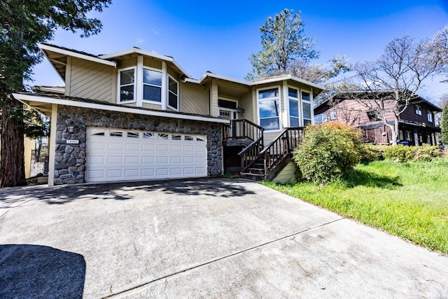 view of front of property featuring stone siding, driveway, and a garage