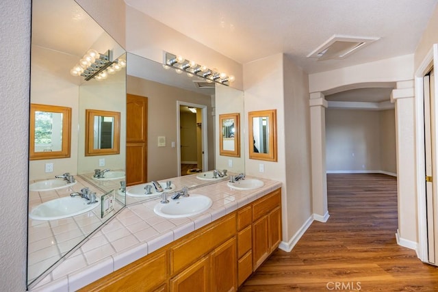 bathroom with double vanity, wood finished floors, and a sink