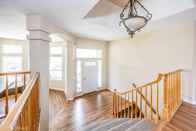 entrance foyer featuring wood finished floors, a healthy amount of sunlight, and ornate columns