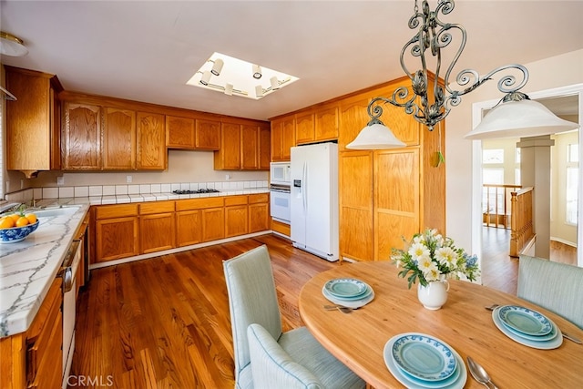 kitchen with white appliances, light countertops, brown cabinets, and dark wood-style flooring