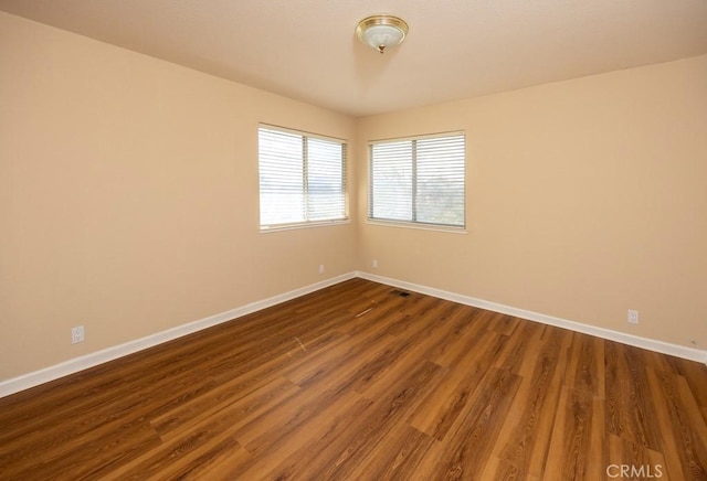 unfurnished room with baseboards and dark wood finished floors