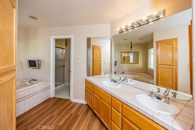 full bathroom with a sink, a garden tub, and wood finished floors