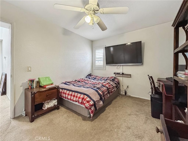 carpeted bedroom with a textured wall, baseboards, and ceiling fan