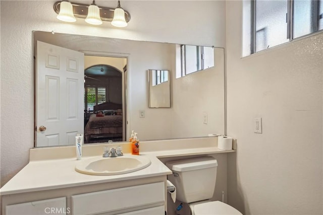 ensuite bathroom featuring vanity, toilet, a textured wall, and ensuite bathroom