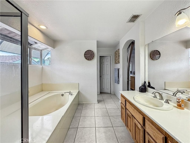 bathroom with tile patterned flooring, visible vents, vanity, a garden tub, and a textured ceiling