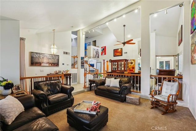 carpeted living room with high vaulted ceiling, rail lighting, visible vents, and ceiling fan