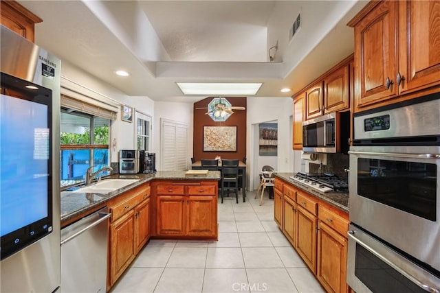 kitchen featuring visible vents, a sink, backsplash, stainless steel appliances, and brown cabinetry