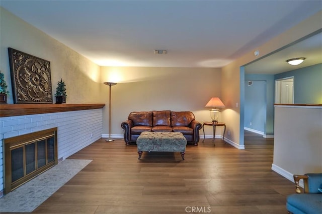 living room with a fireplace, wood finished floors, visible vents, and baseboards