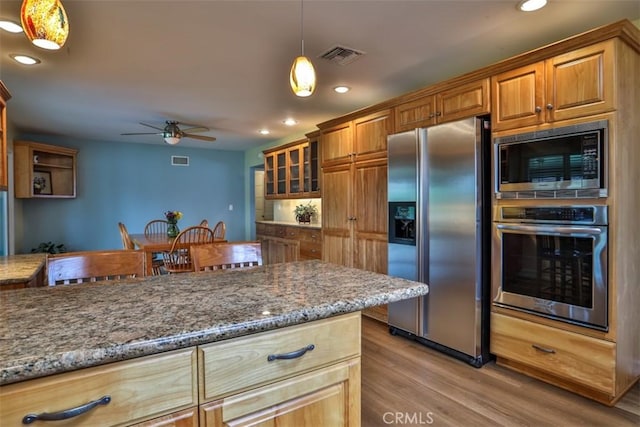 kitchen featuring dark stone countertops, visible vents, ceiling fan, stainless steel appliances, and light wood-type flooring