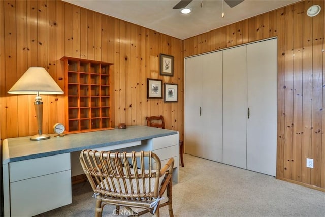 office featuring built in desk, wood walls, and a ceiling fan