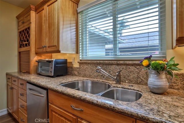 kitchen with a toaster, light stone countertops, a wealth of natural light, and a sink