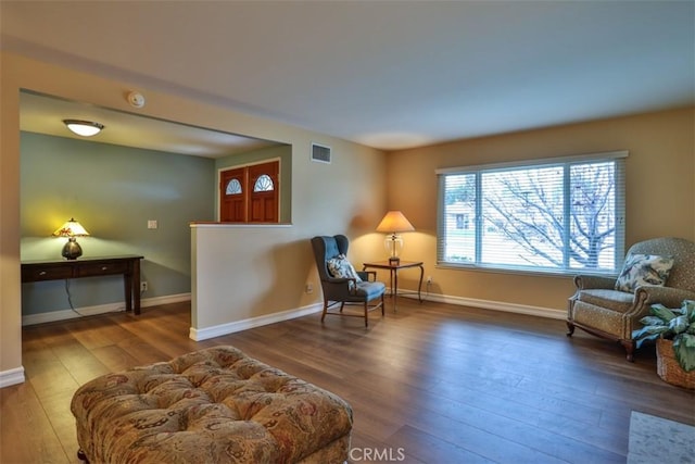 living area featuring hardwood / wood-style floors, baseboards, and visible vents