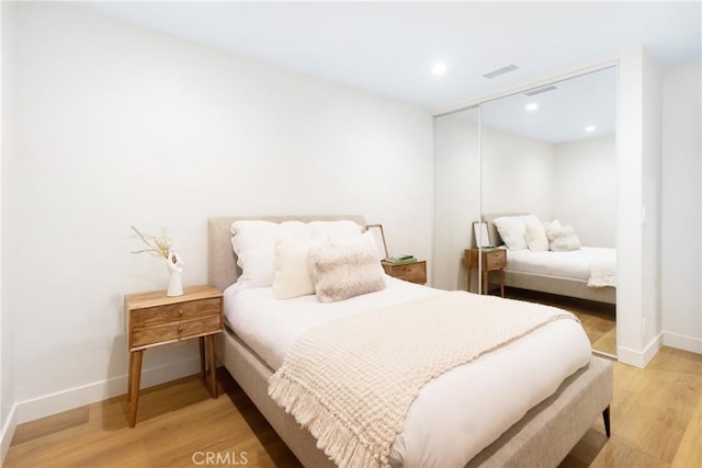 bedroom featuring visible vents, baseboards, light wood-type flooring, and a closet