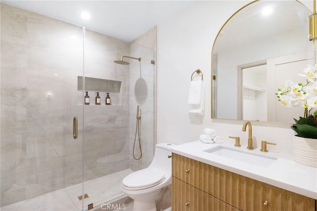 bathroom featuring a shower stall, toilet, and vanity