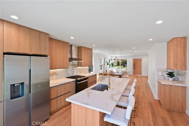 kitchen featuring modern cabinets, stainless steel refrigerator with ice dispenser, a sink, gas range oven, and wall chimney range hood