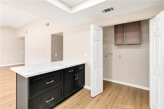 kitchen with light wood-type flooring, visible vents, baseboards, and dark cabinetry