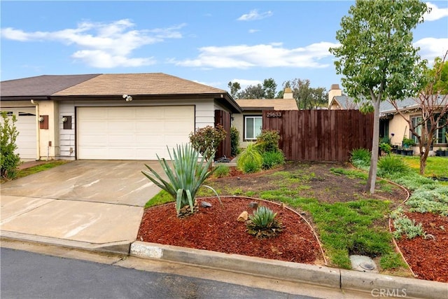 ranch-style house featuring a garage, concrete driveway, and fence